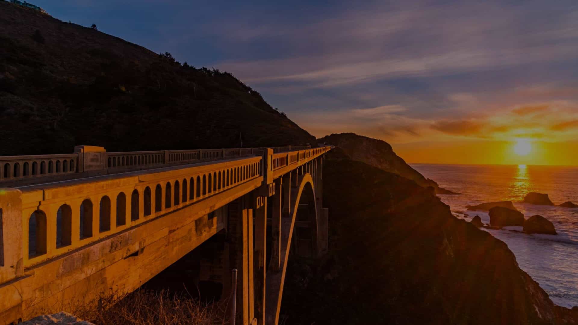 A bridge next to the ocean during sunset