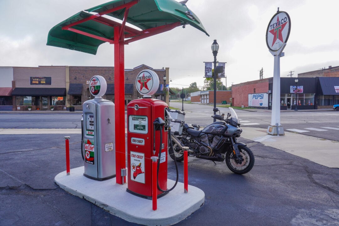 A motorcycle parked behind two pumps at a vintage service station