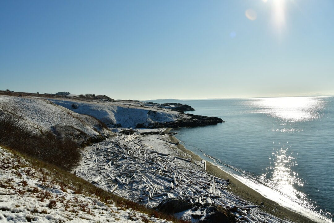 Snow covers the ground on San Juan Island as glistening blue waters surround it