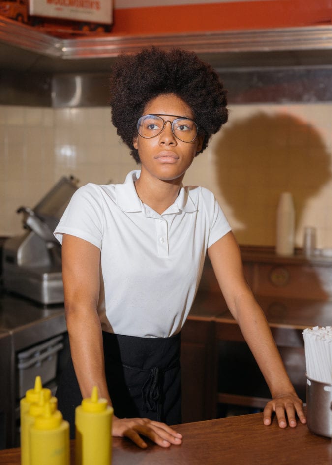 a woman stands behind the counter of the bar at woolworth's diner